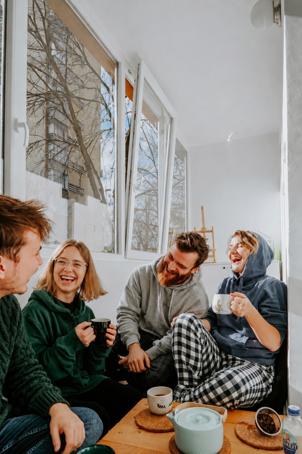 Four friends laughing together over coffee at home
