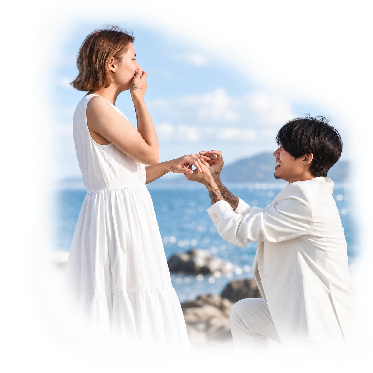 A man kneeling to propose to his partner outdoors beneath a blue sky